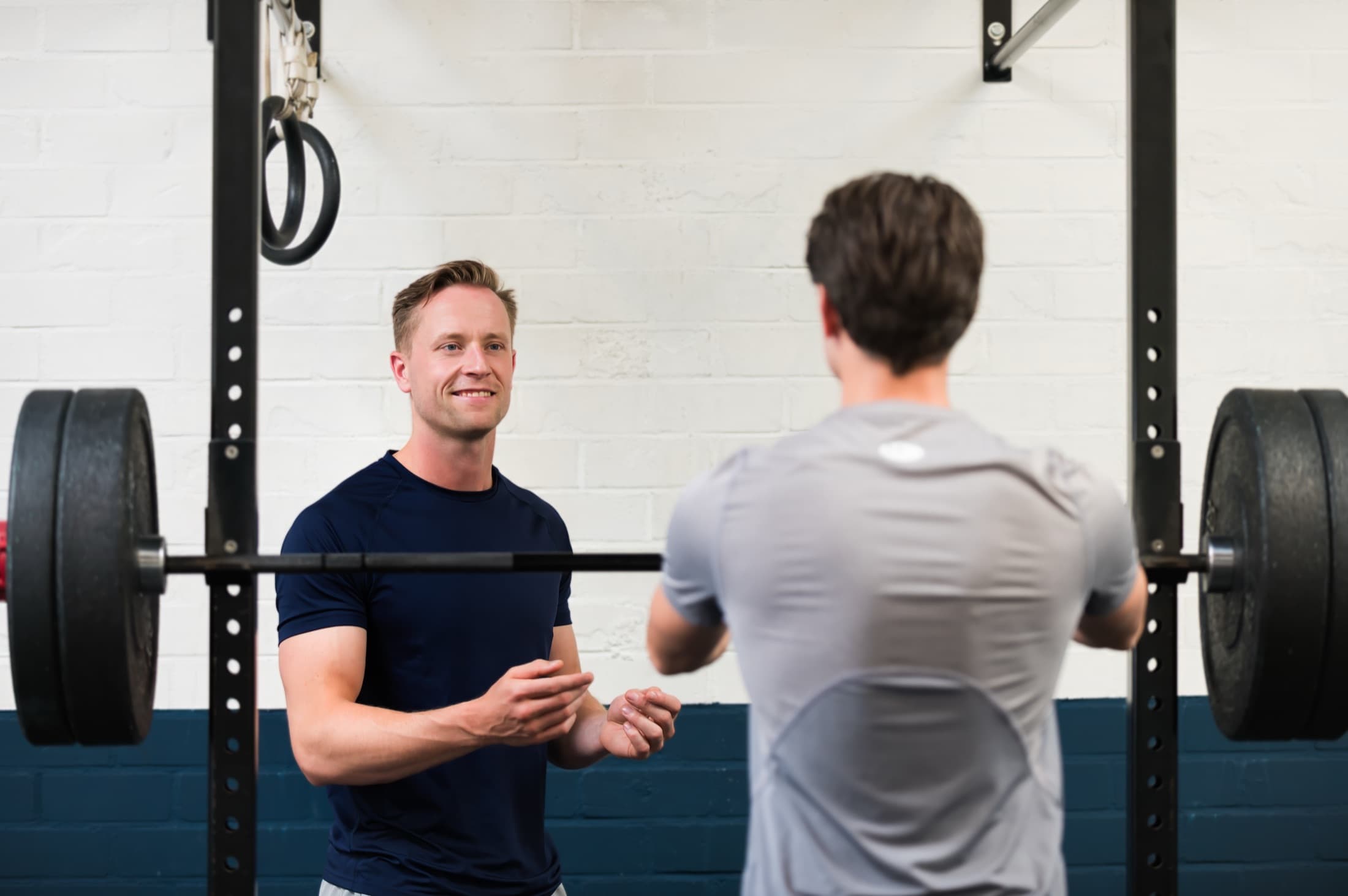 Jelle Stolk coacht een klant bij de squat rack